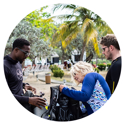 A group of people looking at scuba gear in a park, excited for their next adventure with eco dive Grenada.