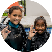 Two girls in scuba gear posing for a picture while scuba diving in Grenada.